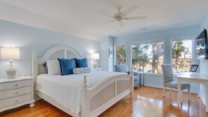 Une chambre à coucher avec un lit blanc, deux tables de chevet, un bureau et une chaise.