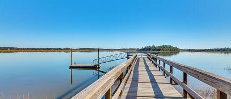 A wooden pier extending into calm water with a clear sky above.