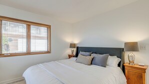 A neatly made bed with a headboard, two bedside tables with lamps, and a window with blinds. - Oceanside Escape w/ Stunning Views: Walk to Beach! (Tillamook)