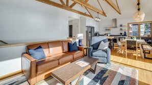 A modern living room with a brown leather sofa, a blue armchair, and a wooden coffee table. - Oceanside Escape w/ Stunning Views: Walk to Beach! (Tillamook)