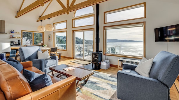 A spacious living room with large windows, a fireplace, and a cozy seating area. - Oceanside Escape w/ Stunning Views: Walk to Beach! (Tillamook)