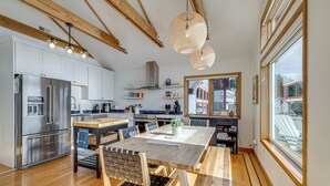 A modern kitchen with stainless steel appliances, wooden beams, and large windows. - Oceanside Escape w/ Stunning Views: Walk to Beach! (Tillamook)