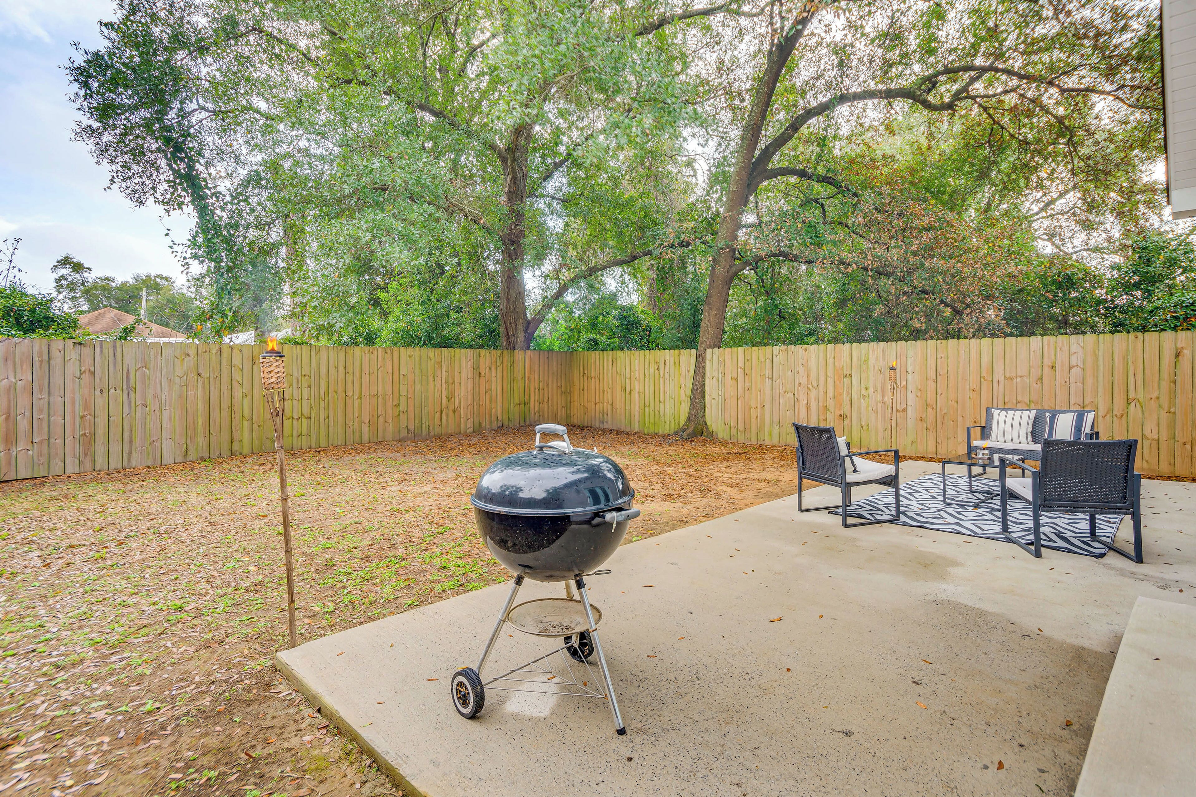 Un jardin avec un barbecue, une table de patio et des chaises.