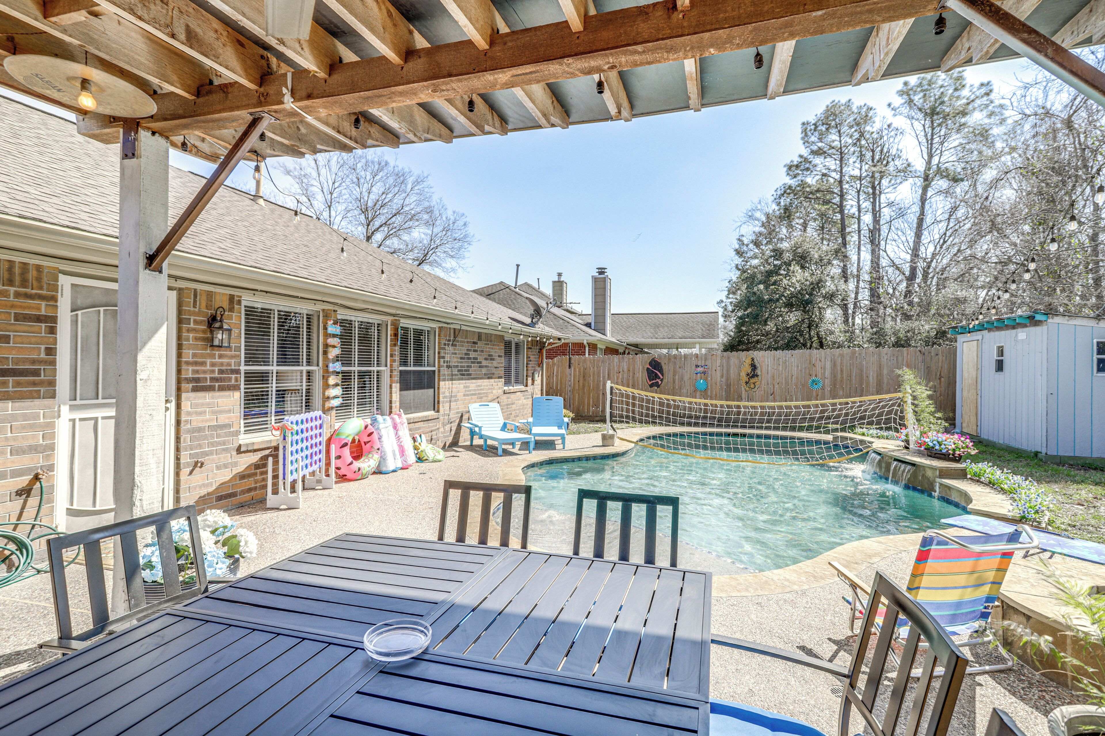 Ein Garten mit Swimmingpool, Holzterrasse und überdachter Terrasse.