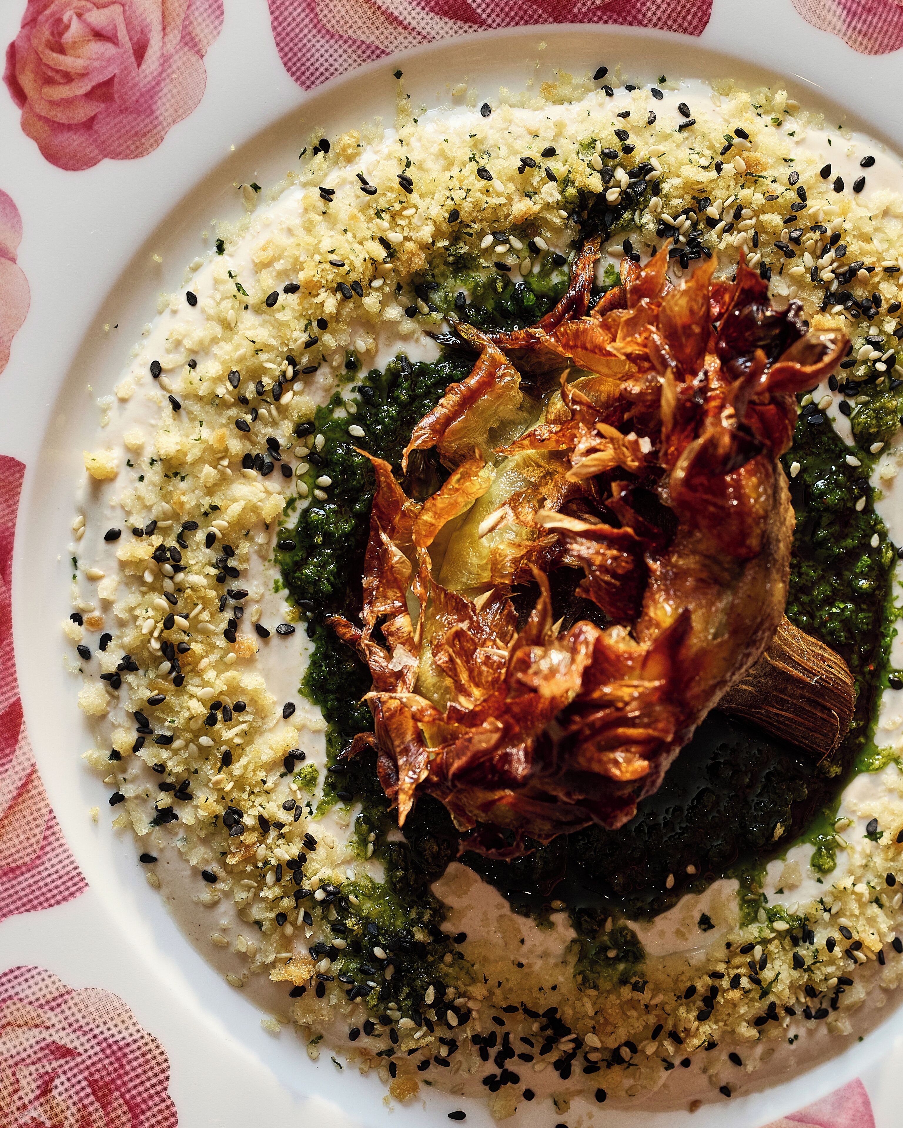 A plate of food with a roasted meat centerpiece, garnished with sesame seeds and herbs.