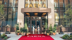 The FAENA hotel entrance with a red carpet, large glass windows, and potted plants. - Faena New York (New York)
