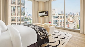 A modern hotel room with a large bed, a small table, and a view of the cityscape. - Faena New York (New York)