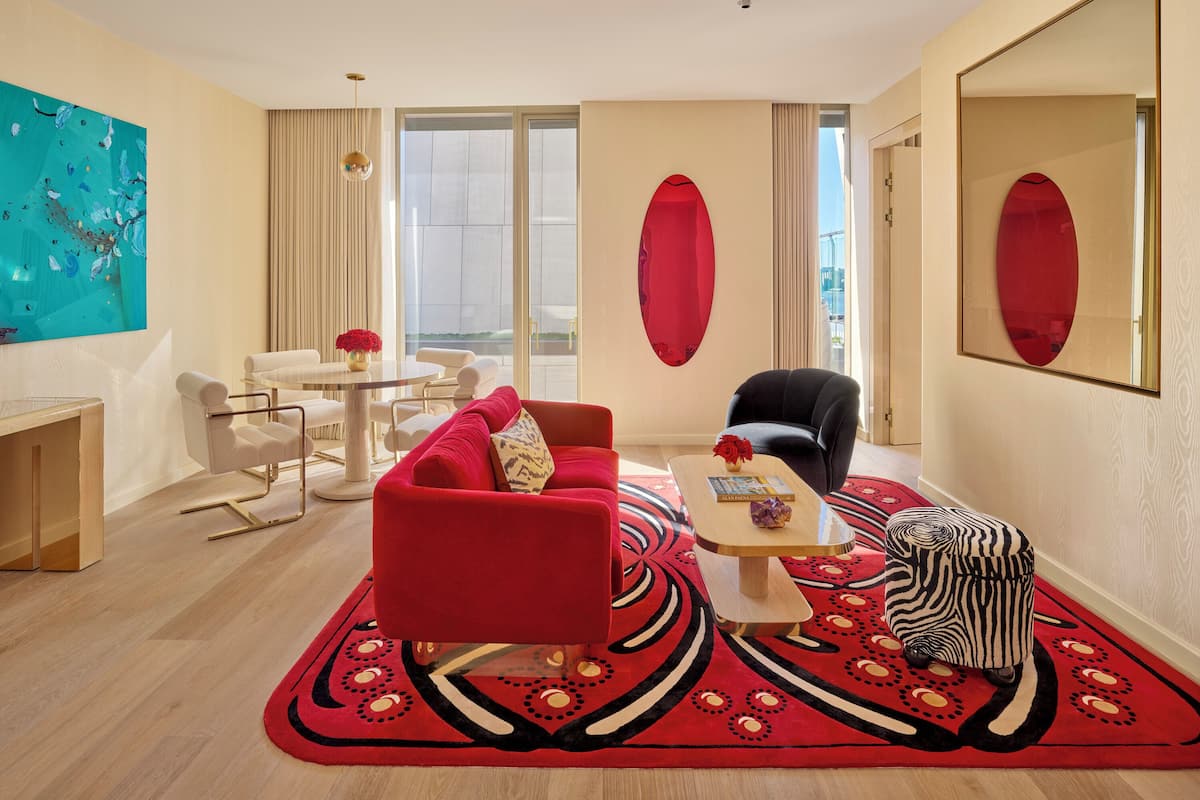Una sala de estar moderna con un sofá rojo, un sillón negro, una mesa redonda de centro y una alfombra estampada.