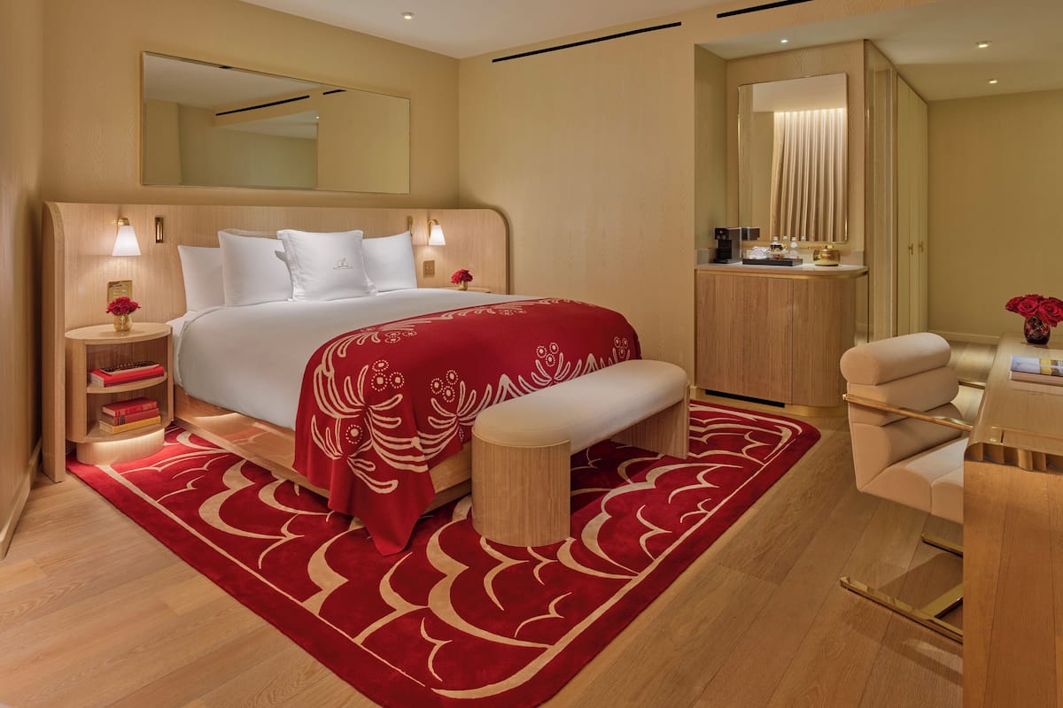 Una habitación de hotel moderna con una cama grande, mesitas de noche, tocador y zona de estar.