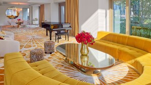 A spacious living room with a yellow sofa, a grand piano, and a large chandelier. - Faena New York (New York)