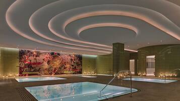 Un moderno vestíbulo de hotel con un mural grande, varias piscinas y un diseño de techo único.