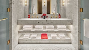 A modern bathroom with a marble sink, dual mirrors, and a towel rack with neatly folded towels. - Faena New York (New York)