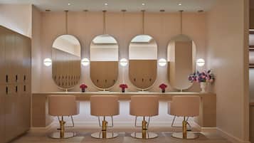 Un baño moderno con cuatro espejos, un tocador y una fila de sillas.