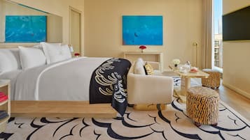 Una habitación de hotel con una cama grande, un sofá, una mesita con un jarrón y un televisor.