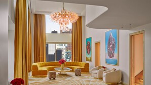 A modern living room with a yellow sofa, a round coffee table, and a chandelier. - Faena New York (New York)