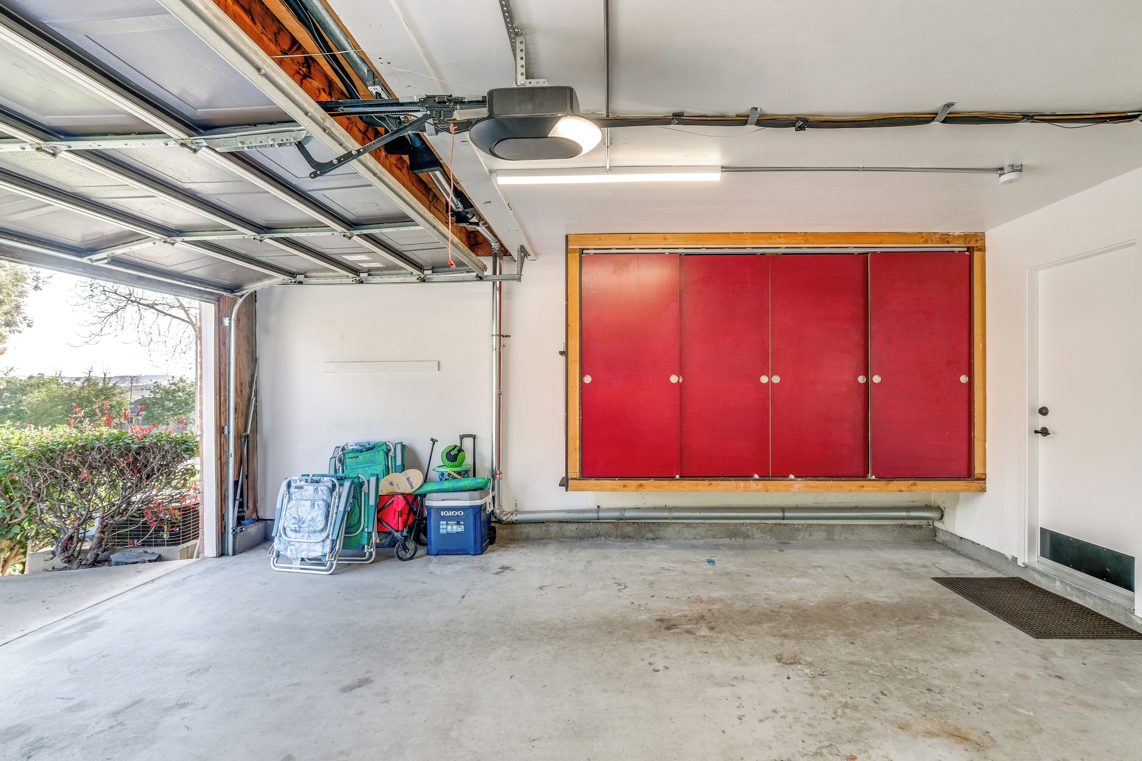 Eine Garage mit roter Tür, Deckenventilator und Betonboden.