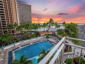A resort pool with multiple levels, palm trees, and a sunset view.