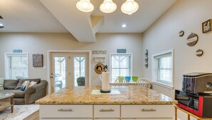 A modern kitchen with a granite countertop, white cabinetry, and a central island.
