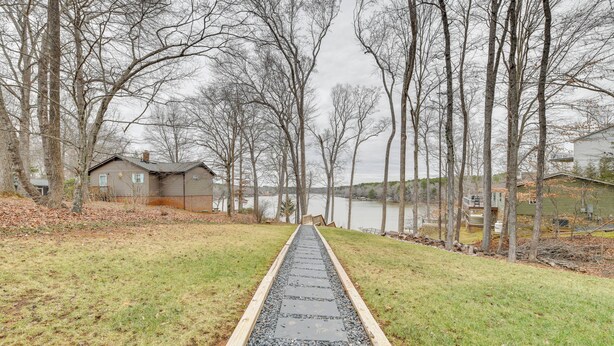 A pathway leading to a house with a view of a lake and trees.