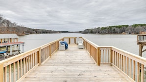 A wooden pier extending into a lake with a view of the surrounding landscape.