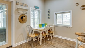 A dining area with a white table, four chairs, and a hat on the wall.