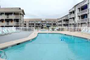 Relax by the pool surrounded by a modern building with balconies and large windows.