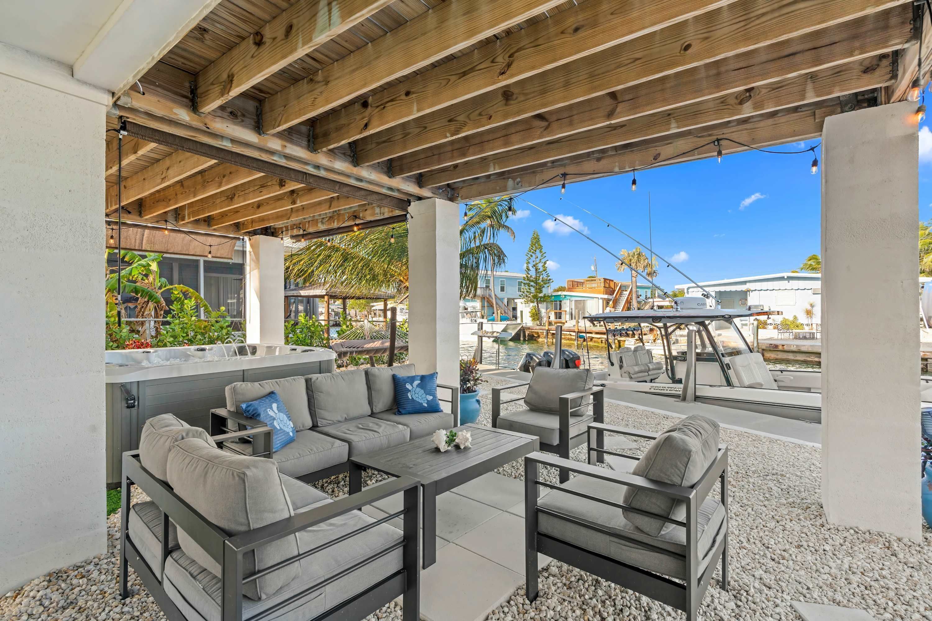 An outdoor patio area with a wooden ceiling, seating arrangements, and a view of the marina.