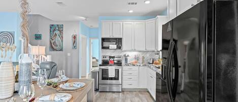 A modern kitchen with white cabinets, stainless steel appliances, and a black refrigerator.