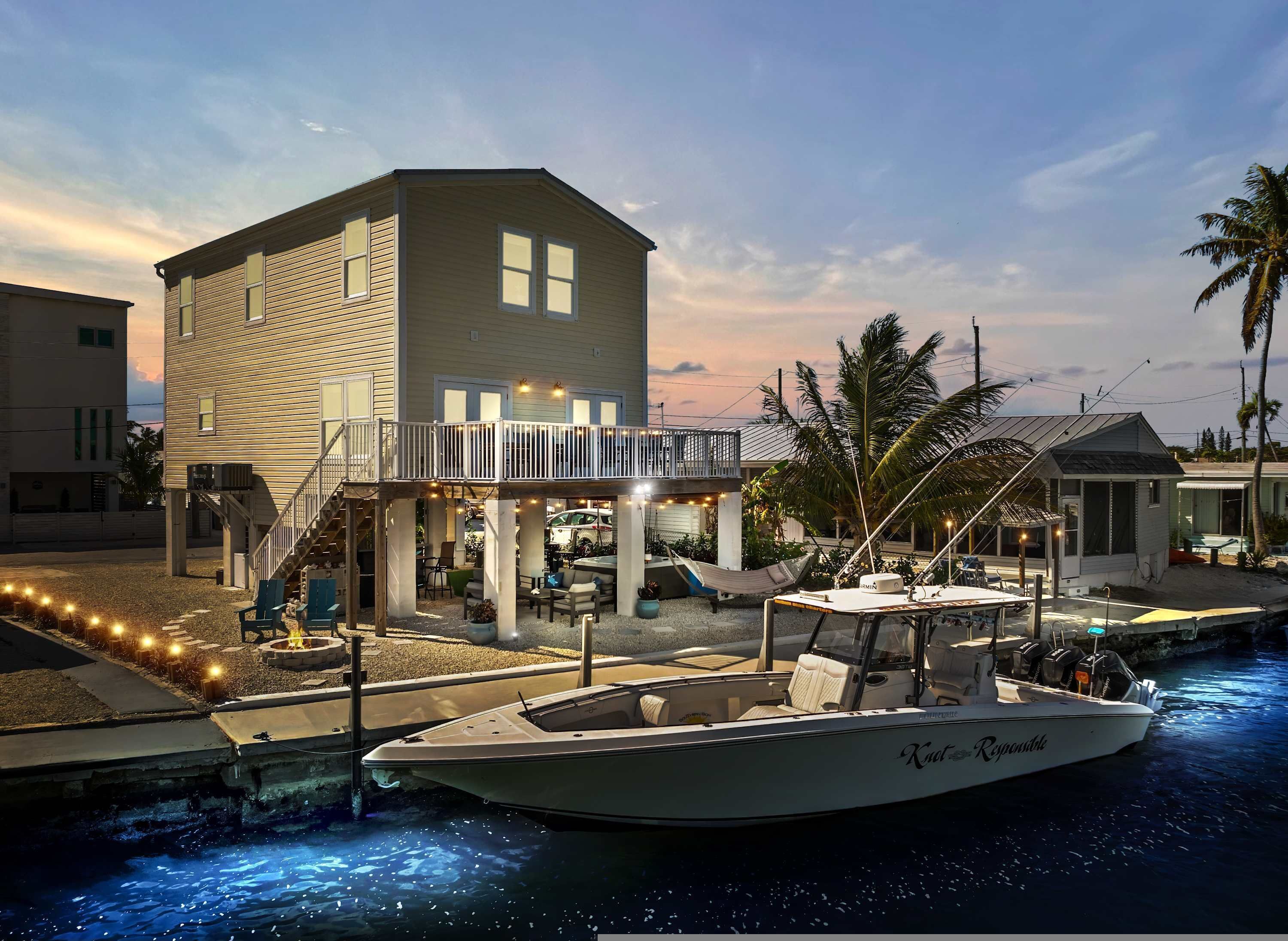 A waterfront property with a boat dock, outdoor seating area, and a two-story building with a balcony.
