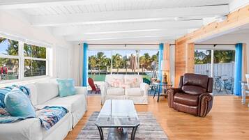 Relax in this spacious living area with a high ceiling, featuring a sofa set, armchair, and glass coffee table.