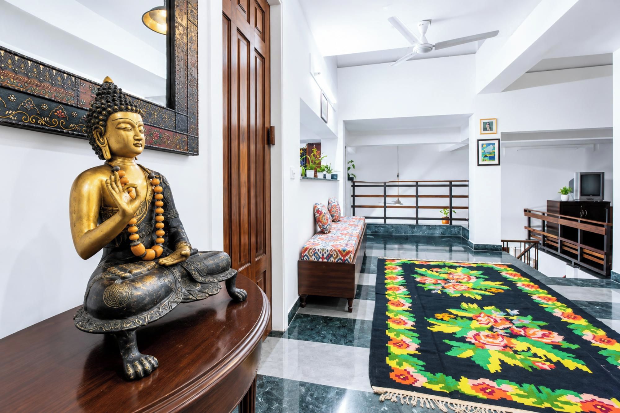 Ein Zimmer mit Buddha-Statue, einem Bett, einem Fernseher und einem Teppich.