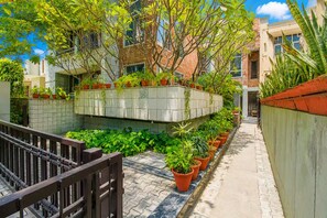 A narrow pathway flanked by potted plants and a brick wall. - Opulent Antique 3br Villa in Gurugram (Gurugram)
