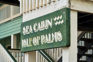 En skylt med texten ”Sea Cabin Isle of Palms”, med grön bakgrund och vita bokstäver.