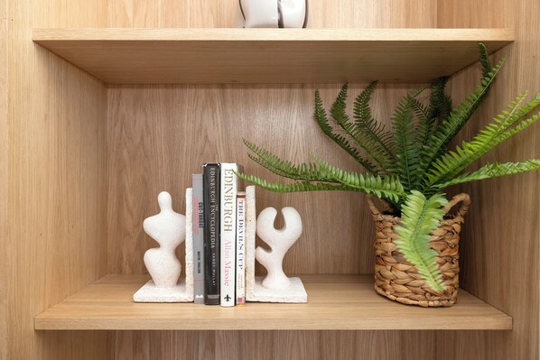 Une étagère en bois avec une fougère en pot et des livres.