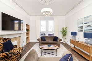 Una sala de estar con televisión de pantalla plana, un sofá, una mesa de centro y una chimenea.
