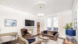 Un salon avec une cheminée, deux canapés, un téléviseur et une grande fenêtre.