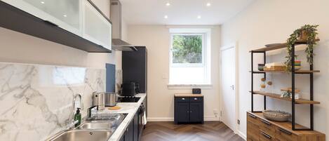 A modern kitchen with a marble countertop, stainless steel sink, and a built-in oven.