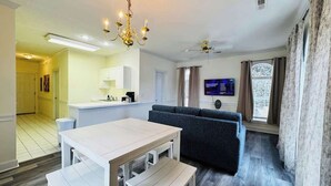 A modern living room with a sofa, a dining table, and a TV.