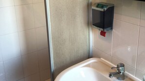 Un bagno con un lavandino bianco, uno specchio e un dispenser di sapone rosso.