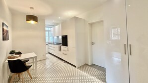 A modern kitchen with white cabinets, a black refrigerator, and a patterned floor. - Business Apartment Solothurn (Solothurn)