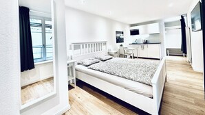 A modern, well-lit bedroom with a large bed, a desk, and a kitchenette. - Business Apartment Solothurn (Solothurn)
