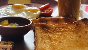 Un vassoio della colazione con pane tostato, uova, una tazza di caffè e una piccola ciotola di marmellata.