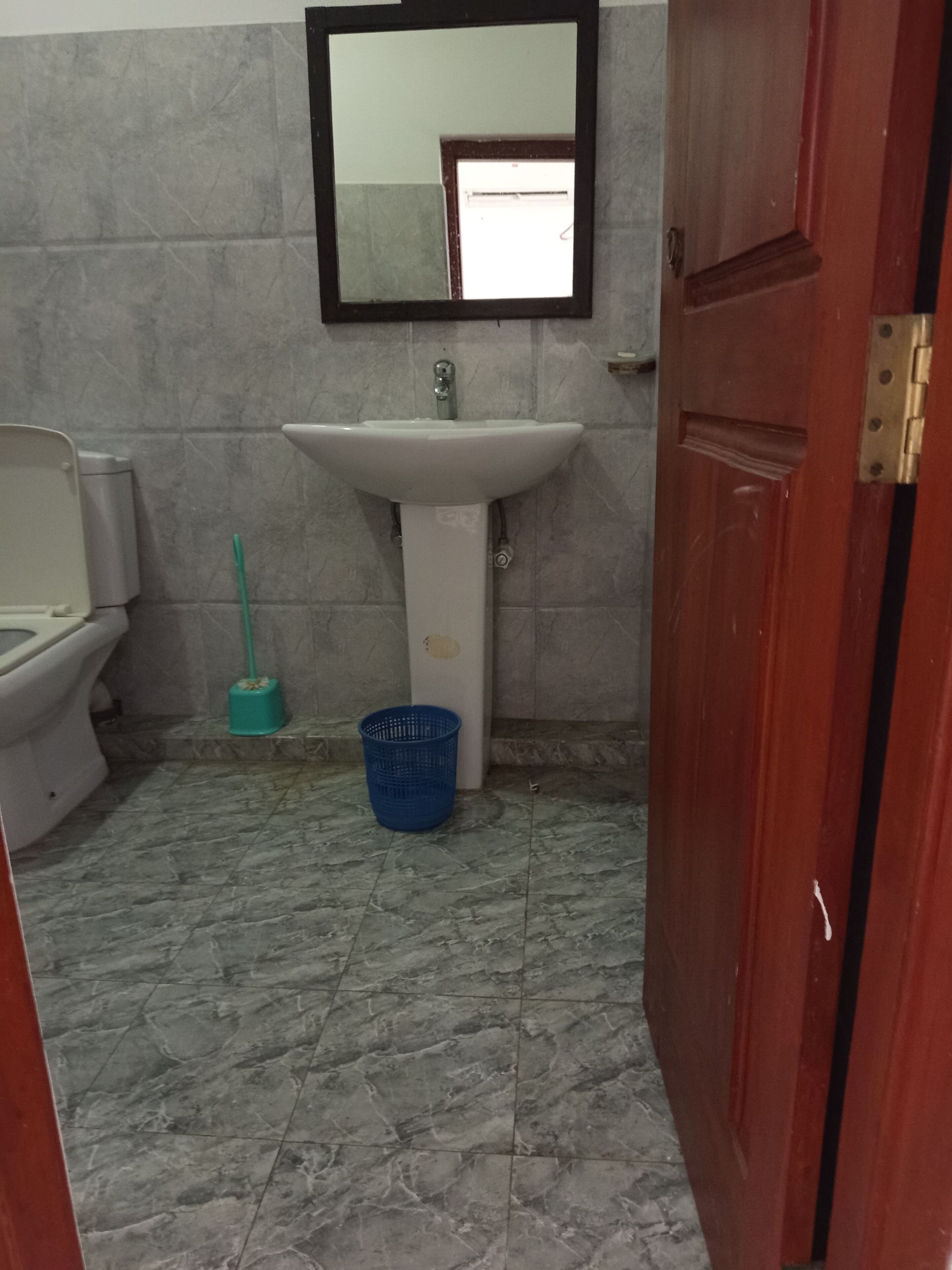 A bathroom with a toilet, sink, and mirror.