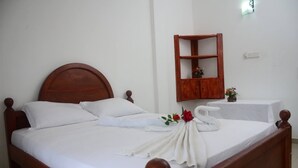 Un letto rifatto con lenzuola bianche, una testiera in legno e un asciugamano decorato con una rosa.