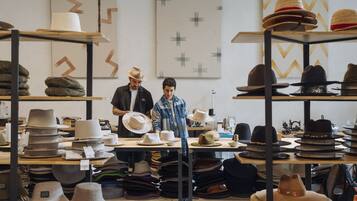 Una tienda de sombreros con estantes llenos de sombreros y una mesa con sombreros.