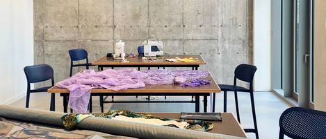A modern workspace with tables, chairs, and sewing equipment.