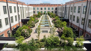 A courtyard with a central garden, surrounded by buildings with large windows and a tiled roof. - aparto Florence Manifattura (Florence)