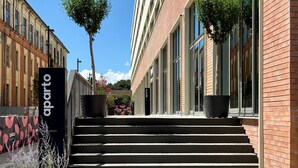 A modern building with a brick facade, large windows, and a staircase leading to the entrance. - aparto Florence Manifattura (Florence)