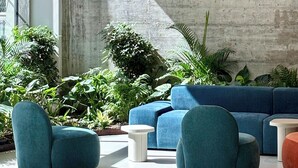 A modern lounge area with blue seating, concrete walls, and indoor plants. - aparto Florence Manifattura (Florence)