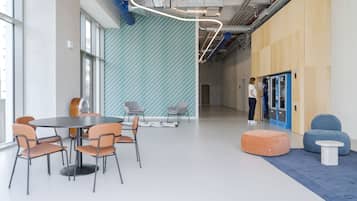 Ein modernes Interieur mit einem runden Tisch und Stühlen, einer Wand mit blau-weißen Mustern und einem blau-weißen Teppich.
